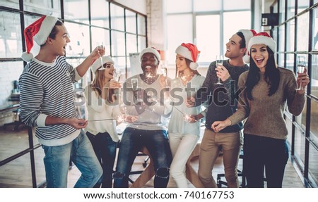 Merry Christmas and Happy New Year 2018! Multiracial young creative people are celebrating holiday in modern office. Group of young business people are drinking champagne in coworking. 