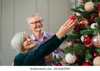 Merry Christmas. Happy senior couple decorated Christmas tree at home. Happy family old man woman near Christmas tree with ornaments. Grandparents celebrating New Year Xmas together. Family moments - Powered by Shutterstock