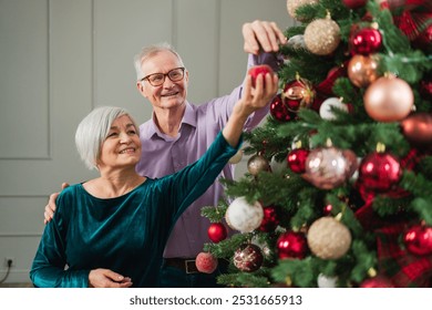 Merry Christmas. Happy senior couple decorated Christmas tree at home. Happy family old man woman near Christmas tree with ornaments. Grandparents celebrating New Year Xmas together. Family moments - Powered by Shutterstock