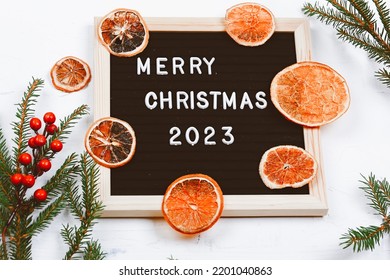 Merry Christmas Lettering On Letter Board. Spruce Branches And Dried Oranges. Minimalistic New Year Background 2023