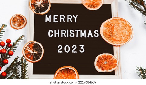 Merry Christmas Lettering On Letter Board. Spruce Branches And Dried Oranges. Minimalistic New Year Background 2023