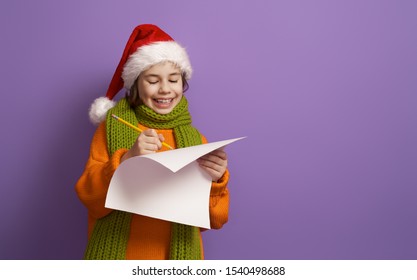 Merry Christmas! Little Girl Is Writing Letter To Santa Claus. Kid On Bright Color Background. Purple, Orange, Green And Red.                               