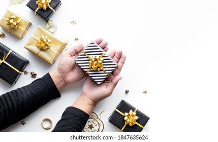 Merry Christmas And New Year Celebration Concepts With Person Hand Holding Gift Box And Ornament In Golden Color On White Background.winter Season And Anniversary Day