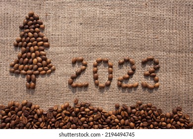 Merry Christmas and New Year greeting card. numbers 2023 and Christmas tree are made from coffee beans on fabric with burlap texture. View from above. New Year concept background - Powered by Shutterstock