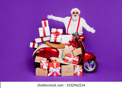 Merry christmas! Photo of fat santa man with many newyear giftboxes on bike congratulating children wear sun specs and red x-mas costume isolated purple background