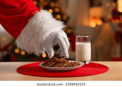 Merry Christmas. Santa Claus taking cookies from plate on table in room, closeup - Powered by Shutterstock