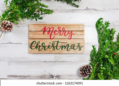 Merry Christmas Sign With Boxwood Greens On White Shiplap Background