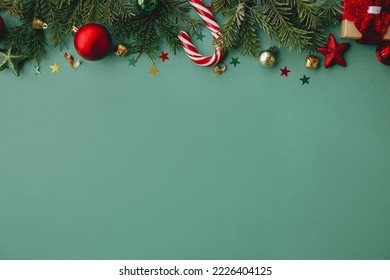 Merry Christmas! Stylish christmas border with festive decorations, confetti, fir branches on green background. Christmas flat lay, seasons greetings card template, space for text