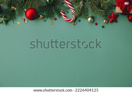 Merry Christmas! Stylish christmas border with festive decorations, confetti, fir branches on green background. Christmas flat lay, seasons greetings card template, space for text