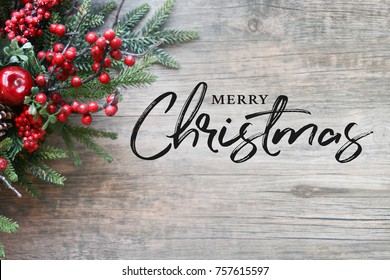Merry Christmas Text with Christmas Evergreen Branches and Berries in Corner Over Rustic Wooden Background - Shutterstock ID 757615597