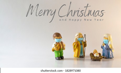Merry Christmas text with figures of a Bethlehem portal, with Saint Joseph, the Virgin Mary and the baby Jesus with hygienic masks due to the Covid-19 pandemic. Concept New Normal - Shutterstock ID 1828971080