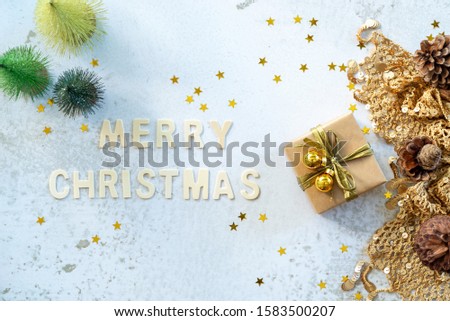 Merry Christmas text with gifts box and shining golden star flakes, X mass background, top view.