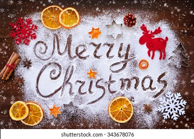 Merry Christmas text made with flour with decorations on cutting board
