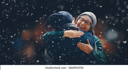 Merry Christmas! Winter portrait of senior couple on snowy dark background.  - Powered by Shutterstock