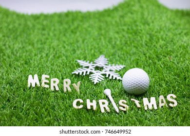 Merry Christmas wording with golf ball and tee on green grass