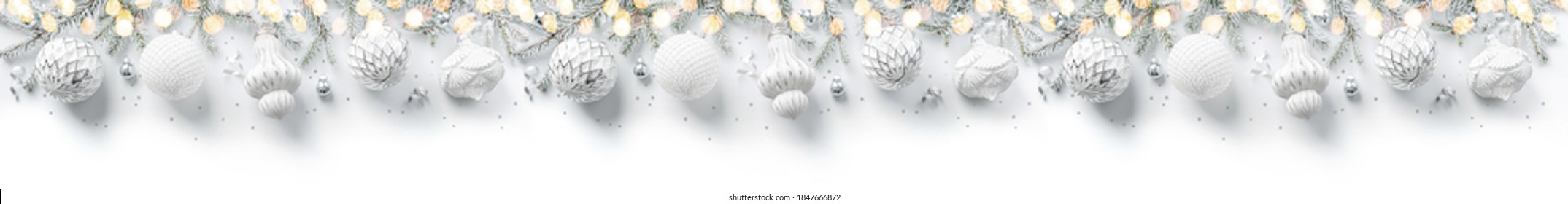 Merry Christmas wreath made of fir branches, white and silver decorations, sparkles and confetti on white background. Xmas and New Year holiday, bokeh, light. Flat lay, top view, wide banner - Powered by Shutterstock