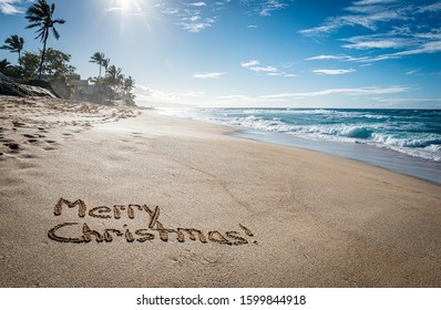 Merry Christmas Written In The Sand On Sunset Beach In Hawaii With Palm Trees And The Ocean In The Background