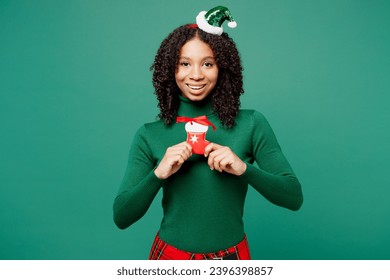 Merry cool little kid teen girl wear hat casual clothes posing hold in hand traditional cookie isolated on plain green background studio portrait. Happy New Year celebration Christmas holiday concept - Shutterstock ID 2396398857