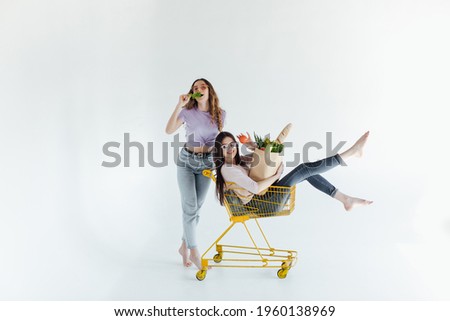 Merry curly women fooling around in weekend. Two best friends enjoying shopping.