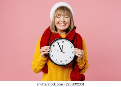 Merry elderly woman 50s year old wear yellow knitted sweater red scarf Santa hat posing hold in hand clock make wish close eyes isolated on plain pink background. Happy New Year Christmas 2023 concept - Powered by Shutterstock