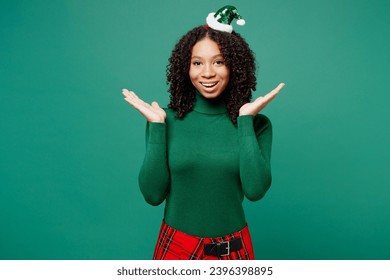 Merry excited shocked little kid teen girl wear turtleneck hat casual clothes posing spread hands say wow isolated on plain green background studio portrait. Happy New Year celebration holiday concept - Shutterstock ID 2396398895