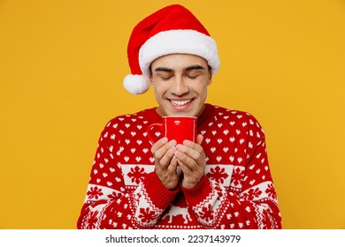 Merry fun young man wear red knitted Christmas sweater Santa hat posing hold in hand cup of tea close eyes sniff isolated on plain yellow background. Happy New Year 2023 celebration holiday concept - Powered by Shutterstock