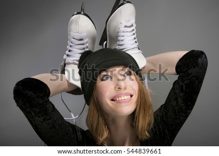Merry girl in black hat with white skates for skating on ice.