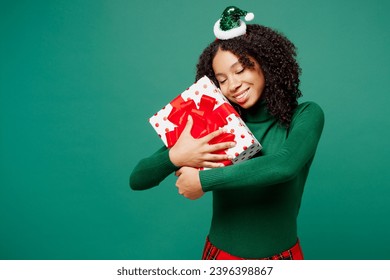 Merry little kid teen girl wears hat casual clothes posing hold hug present box with gift ribbon bow isolated on plain green background studio portrait. Happy New Year celebration Christmas concept - Shutterstock ID 2396398867