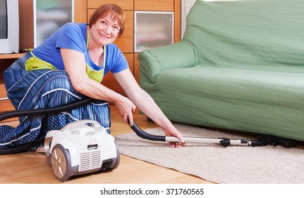 Merry Mature Woman Vacuuming The Room