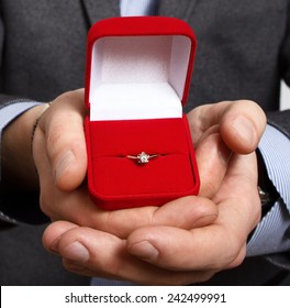 Merry Proposal. Male Hand Holds Out The Engagement Ring In Red Box