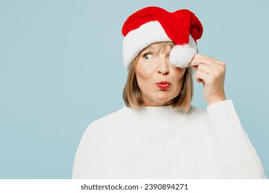 Merry surprised cool elderly woman 50s years old wear sweater cover eyes with Santa hat pompom posing look aside isolated on plain blue background studio. Happy New Year celebration holiday concept - Powered by Shutterstock