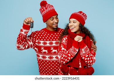 Merry young couple two man woman wear red Christmas sweater Santa hat posing give gift car keys fob keyless system isolated on plain pastel light blue background. Happy New Year 2023 holiday concept - Shutterstock ID 2223916431