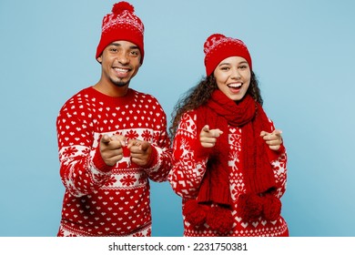 Merry young couple two man woman wear red Christmas sweater Santa hat posing point index finger camera on you motivating isolated on plain pastel blue background. Happy New Year 2023 holiday concept - Shutterstock ID 2231750381