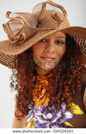 Merry young woman is wearing a summer variegated dress and the hat wide-brimmed.