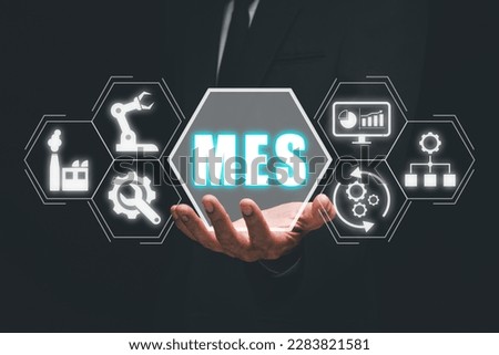 MES - Manufacturing Execution System concept, Businessman hand holding Manufacturing Execution System icon on virtual screen.
