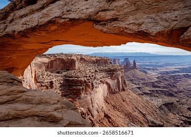 Mesa Arch frames the breathtaking view of Canyonlands National Park, USA, showcasing dramatic red rock formations and deep canyons under soft natural light—captured using landscape photography