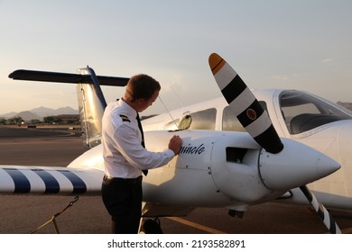 MESA, ARIZONA, USA - 22 July 2022: Commercial Student Pilot Checking The Oil On One Of The Engines Of A Twin Engine Piper Seminole On The Ramp At Falcon Field Airport 