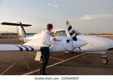 
MESA, ARIZONA, USA - 22 July 2022: Commercial Student Pilot Checking The Oil On One Of The Engines Of A Twin Engine Piper Seminole On The Ramp At Falcon Field Airport