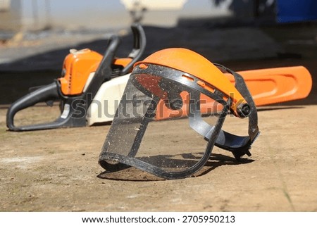 Mesh face shield or full face mesh with chainsaw in the background showing the concept of safety
