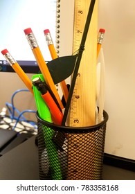 Mesh Pencil Holder Filled With Pencils, Pens, And Misc. Office Trinkets. 