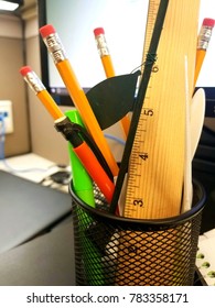 Mesh Pencil Holder Filled With Pencils, Pens, And Misc. Office Trinkets. 