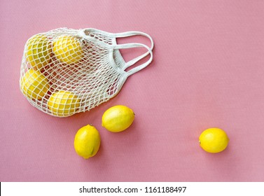 Mesh shopping bag with lemons on pink canvas background. - Powered by Shutterstock