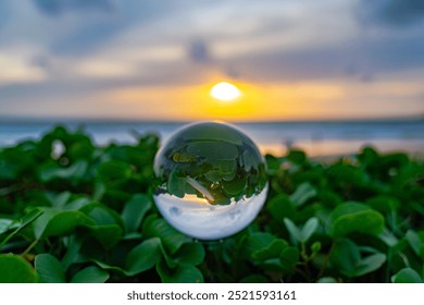 A mesmerizing beach sunset viewed through a crystal ball, capturing the warm hues of the sky and the reflection of the ocean, creating a unique and artistic perspective.
