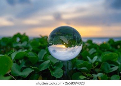 A mesmerizing beach sunset viewed through a crystal ball, capturing the warm hues of the sky and the reflection of the ocean, creating a unique and artistic perspective.