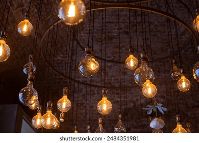 A mesmerizing collection of incandescent bulbs hangs from a circular fixture, illuminating a brick-walled room in Moscow, Russia, casting a warm and inviting glow. - Powered by Shutterstock