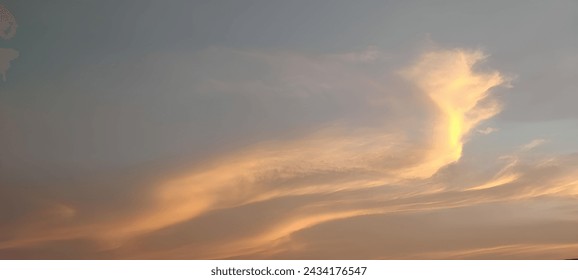 황혼의 하늘을 매료시키는 것: 청회색에 대한 부드럽고 금빛 구름. 동적인 형성은 평온함을 불러일으킨다. 스톡 사진