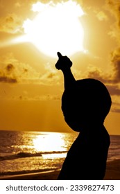A mesmerizing image of a young boy, his silhouette etched against a vibrant backdrop of the setting sun, his finger reaching out to the captivating screen.