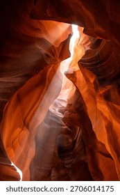 Mesmerizing sandstone formations inside Antelope Canyon, where soft beams of sunlight reveal the canyon’s swirling textures and radiant orange tones. The sculpted rock curves create an abstract, dream