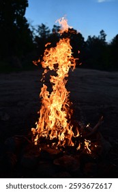 A mesmerizing scene of an intense fire burning brightly against a night sky, with smoke rising from the flames