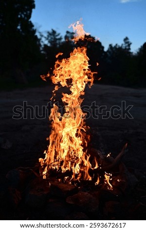 A mesmerizing scene of an intense fire burning brightly against a night sky, with smoke rising from the flames